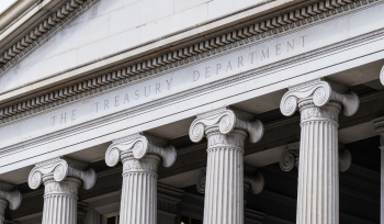 Stone facade of a government building with tall fluted Ionic columns and the inscription 'The Treasury Department' above the entrance